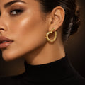 Modelo usando o brinco Argola Aura folheado a ouro, com contorno orgânico e textura em relevo, vendido por par.