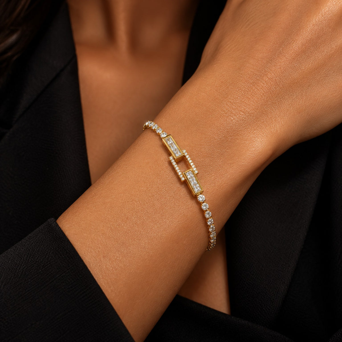 Pulseira Eloá folheada a ouro no pulso de uma modelo, com zircônias incolores e detalhe central de elementos retangulares.