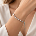 Pulseira Estela em aço inoxidável prateado no pulso de uma modelo, com estrelas de quatro pontas alternadas com zircônias incolores.